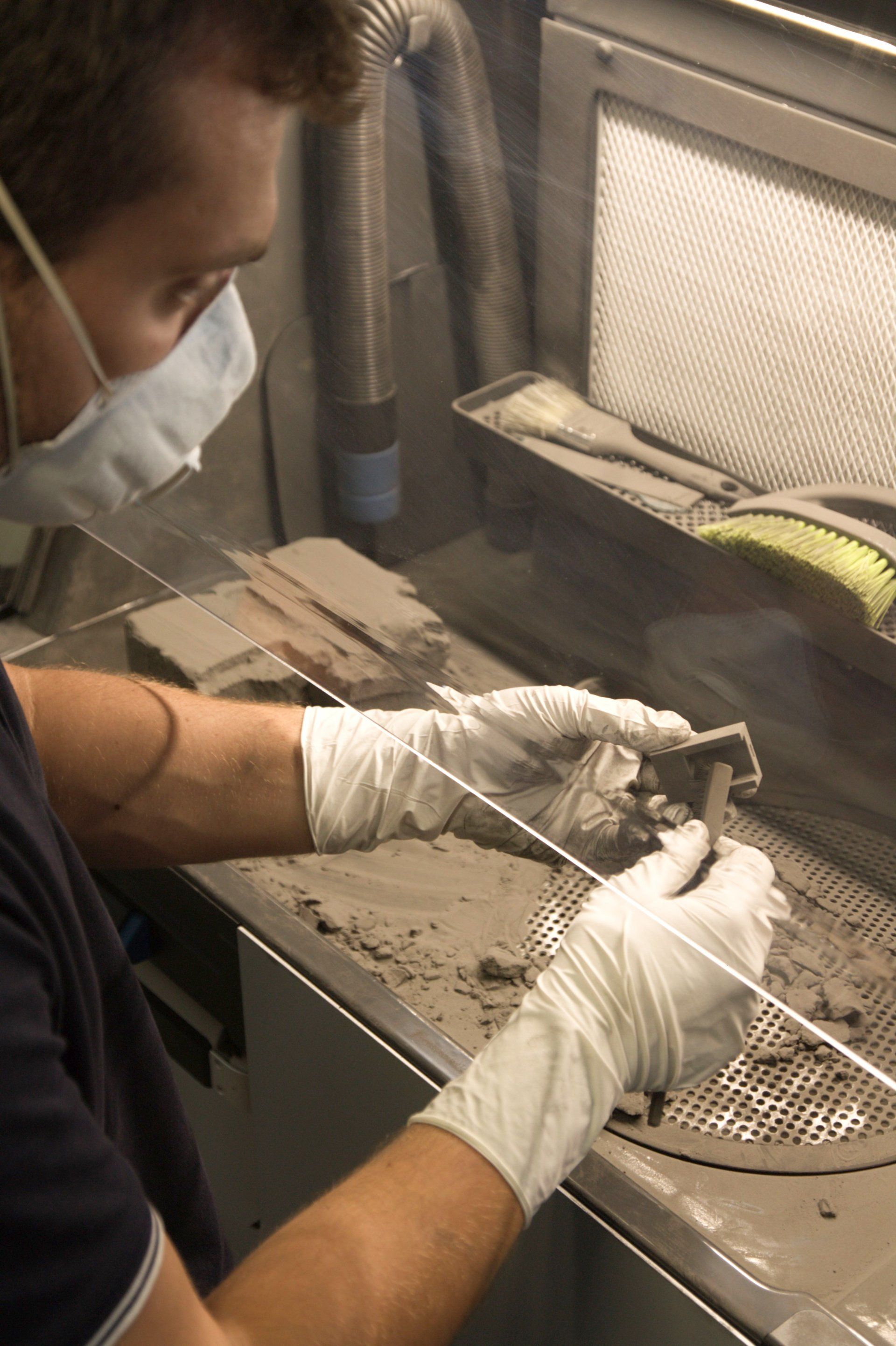 Opérateur en train de réaliser la finition d'une pièce fabriquée par frittage poudre (SLS)