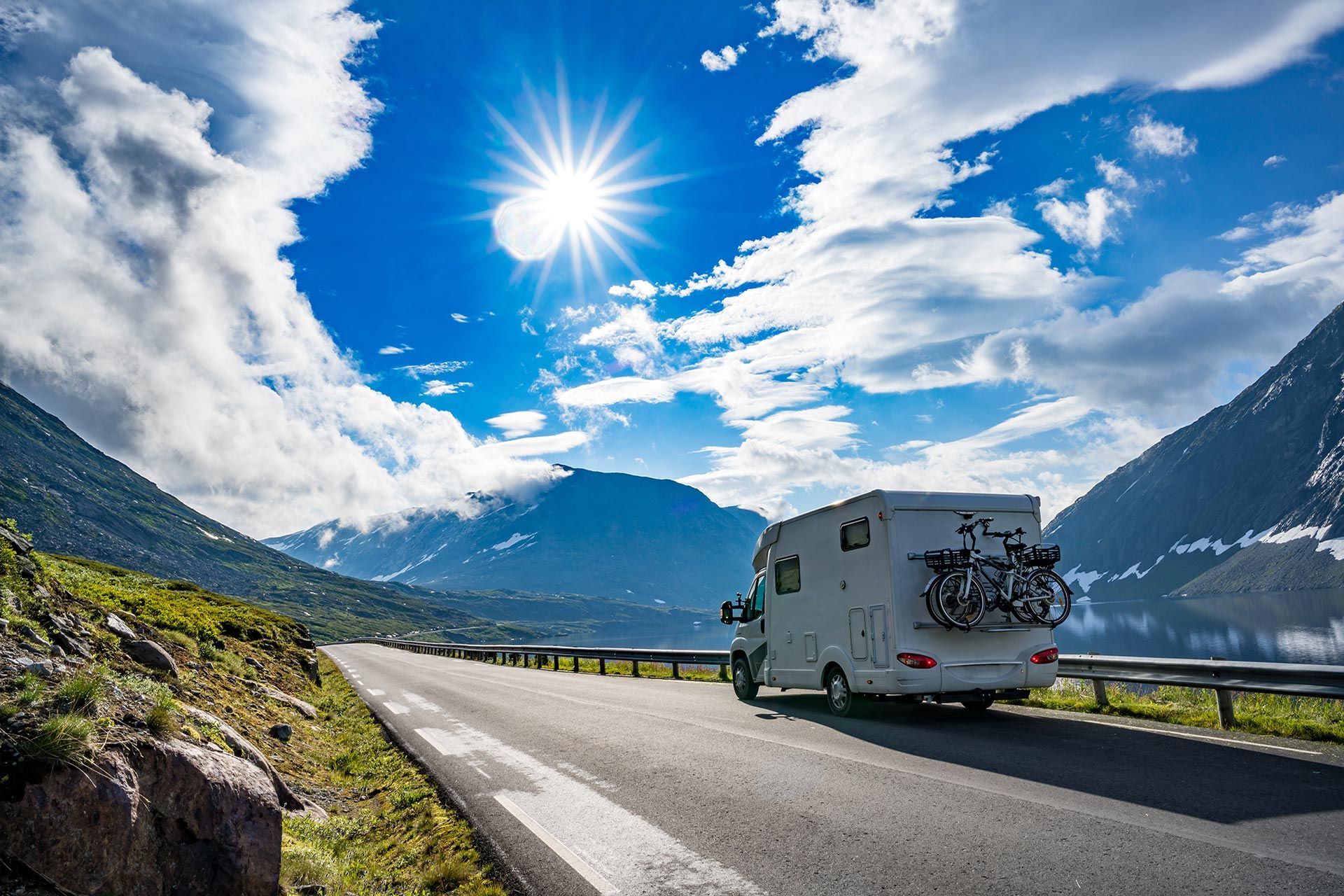 Ein Wohnmobil aud der Landstrasse am See mit vielen Bergen