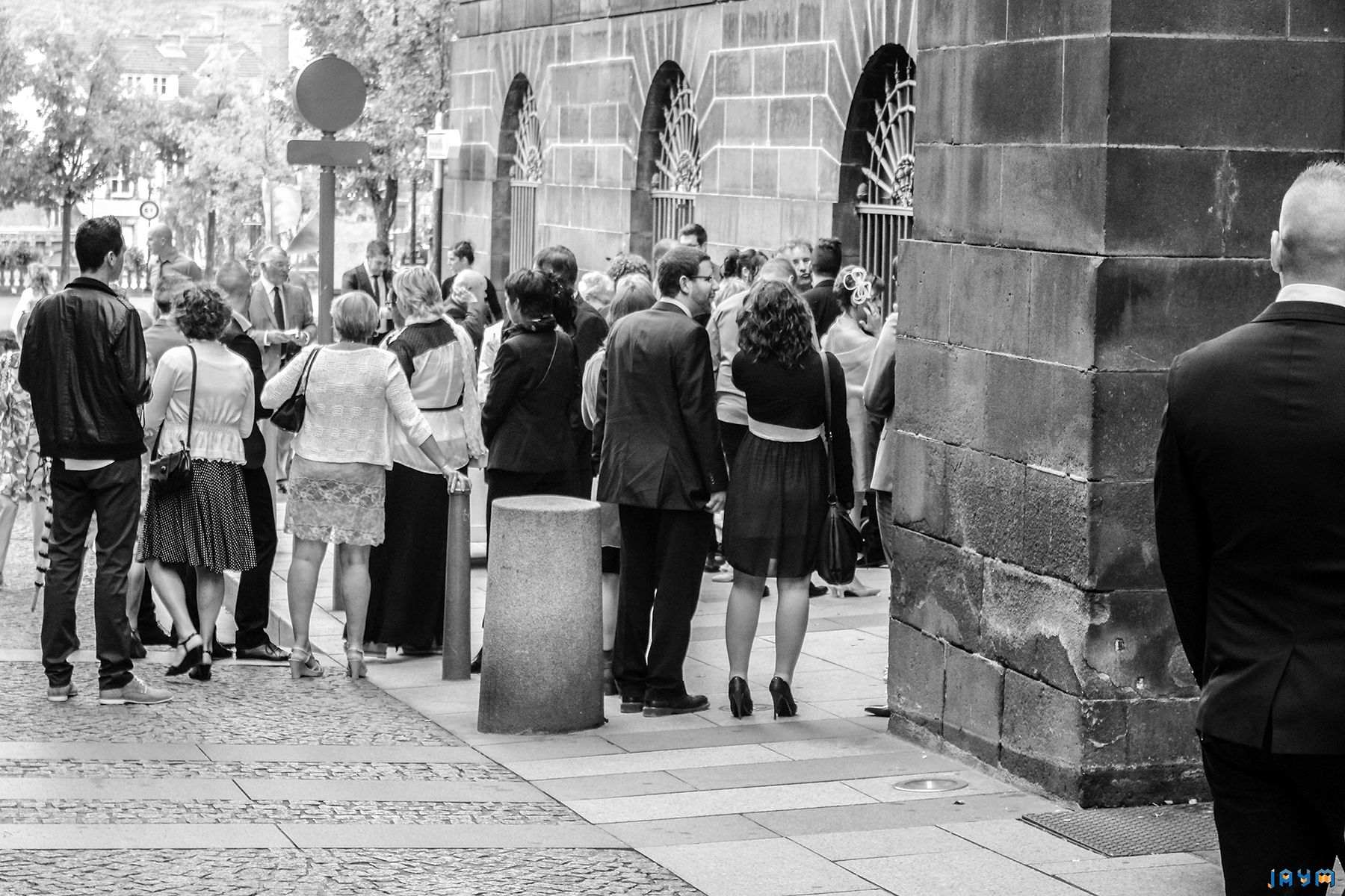 Portrait de groupe des invités réunis sur le parvis de l'Hôtel de Ville de Clermont-Ferrand. Cette photo souligne le contraste entre les tenues de cérémonie élégantes et l'architecture sombre et authentique de la pierre de Volvic.