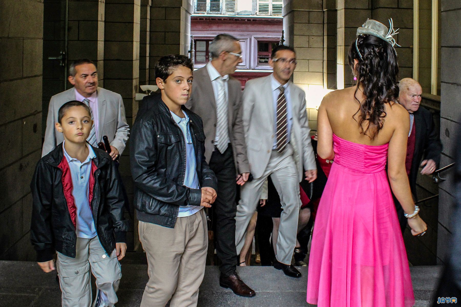 Moment de partage intense sur le parvis de l'Hôtel de Ville de Clermont-Ferrand. Les mariés, Clémentine et Nicolas, sont entourés par l'affection de leurs invités juste après leur union civile. Une photographie authentique qui illustre la joie communicative d'un mariage en Auvergne et la convivialité des félicitations.