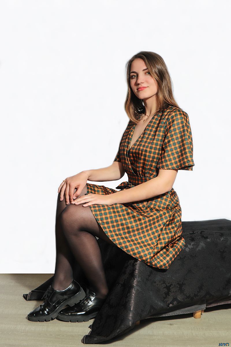 Shooting de Dina Une jeune fille en petite robe à motifs assise sur un pouf carré