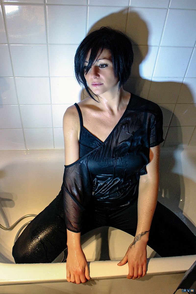 Toute mouillée, habillée dans une baignoire.