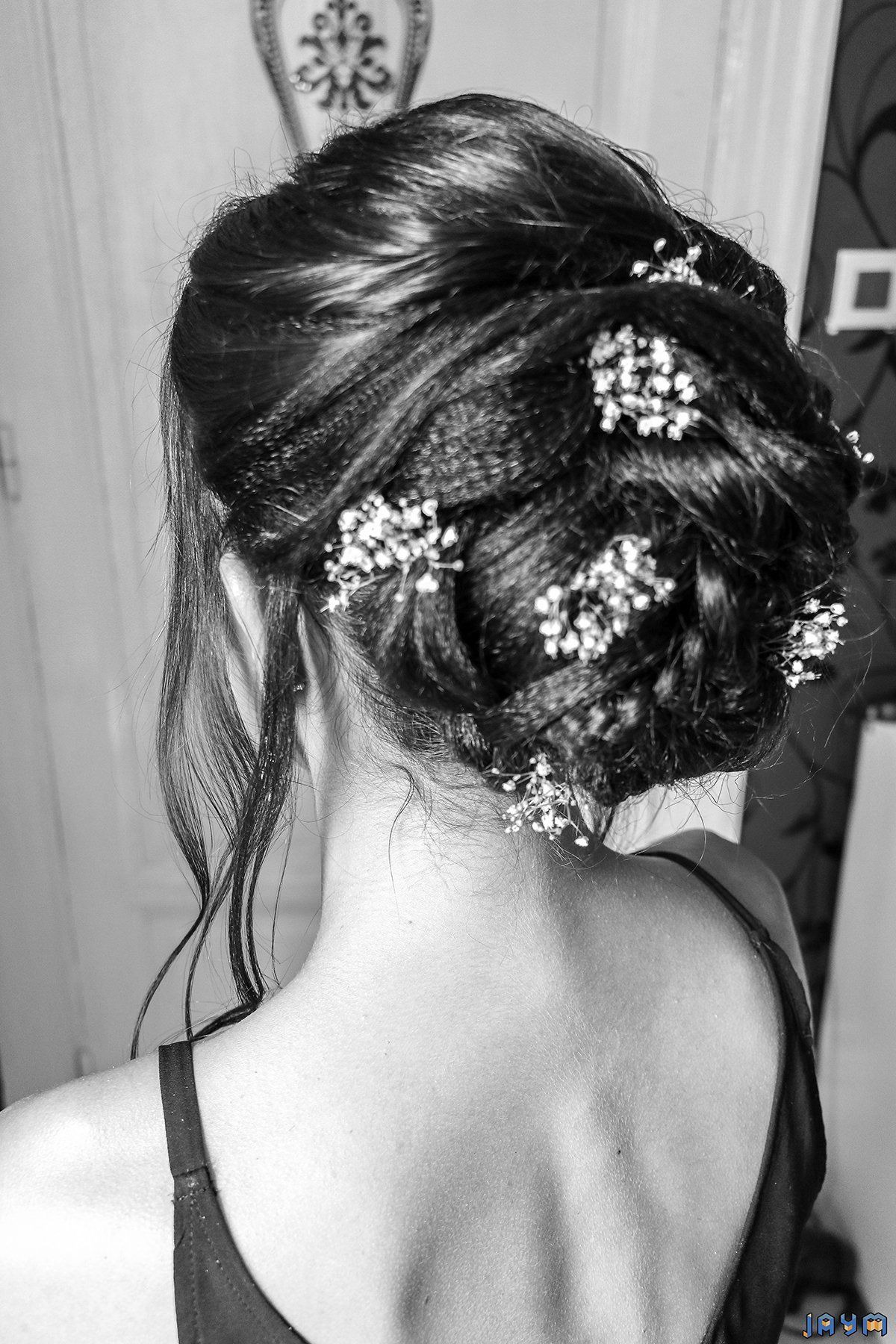 Mise en forme du chignon de la mariée avec des nattes et des petites fleurs.
