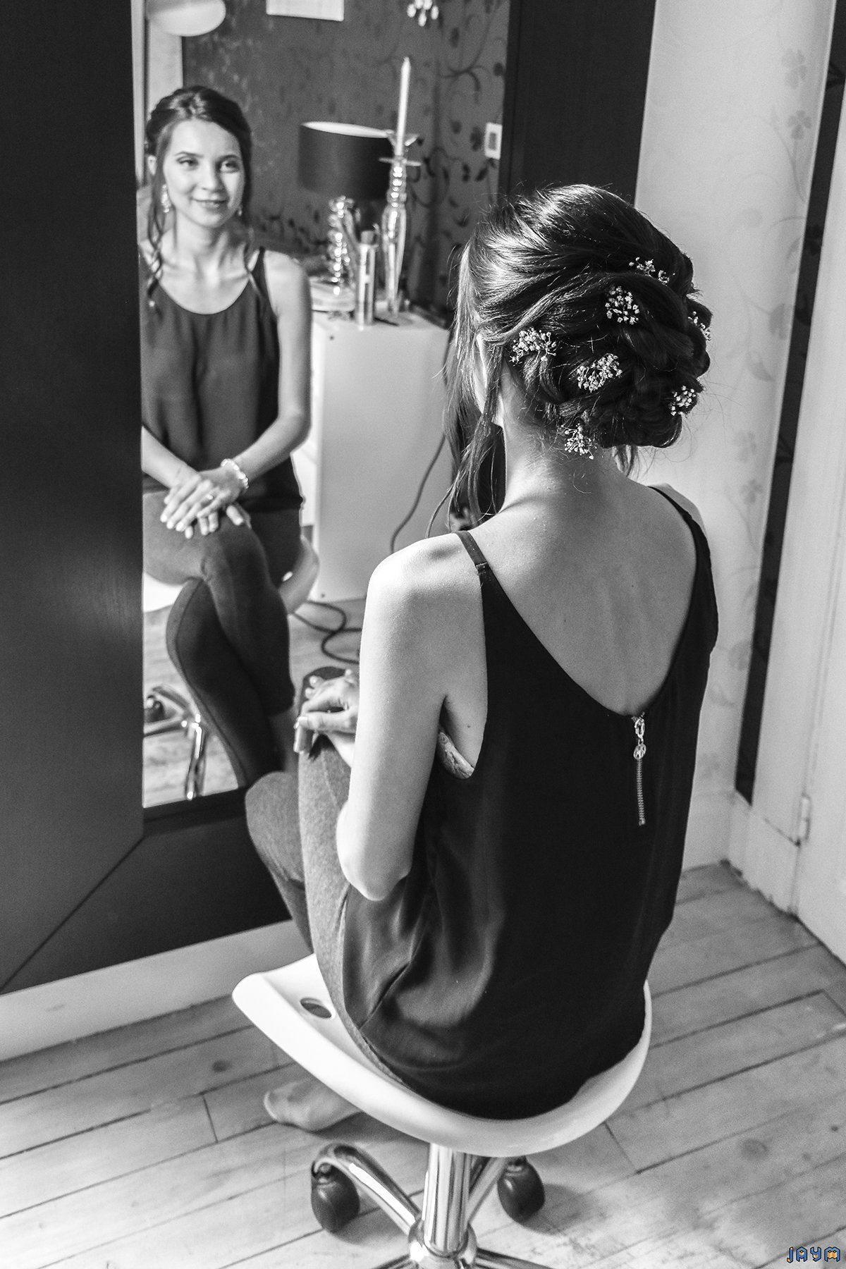 La mariée sourit en voyant sa jolie coifffure, un chignon magnifique.