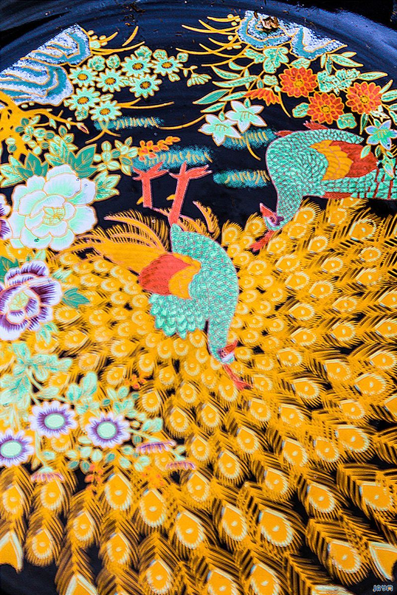 Photographie contrastée en noir et blanc d'une assiette ornementale illustrant des oiseaux exotiques et des motifs floraux finement détaillés, mettant en relief le travail de gravure.