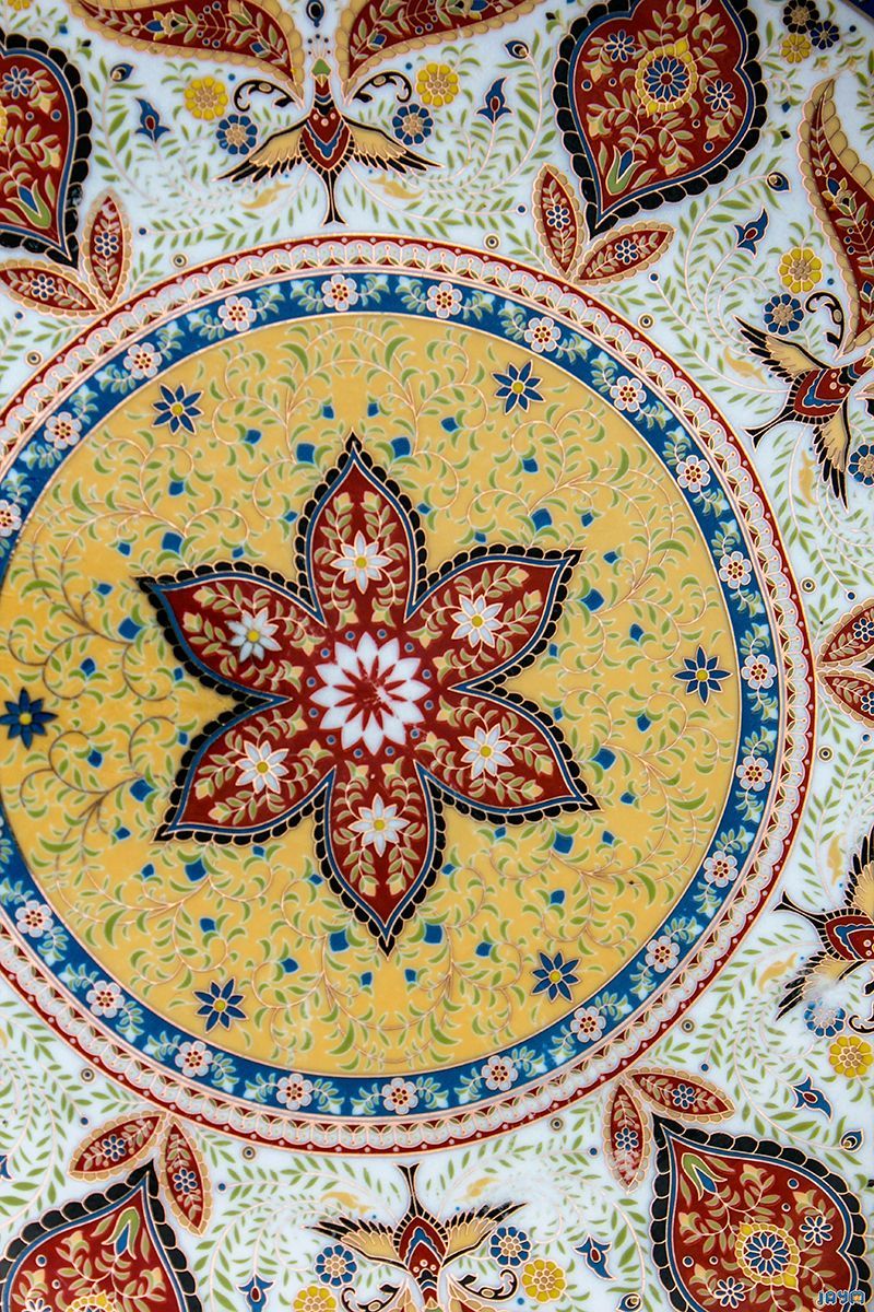 Gros plan vertical d'un carrelage de faïence blanche orné de motifs géométriques réguliers bleu azur, alternant losanges et étoiles à huit branches.