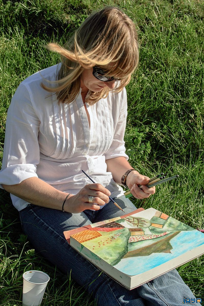 Assise dans l'herbe l'artiste reproduis les paysages du puy-de-dôme