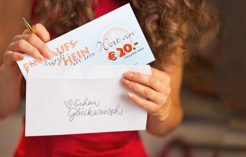 Eine Frau steckt einen 20 Euro Gutschein des Wirtschaftsring in einen Briefumschlag auf dem