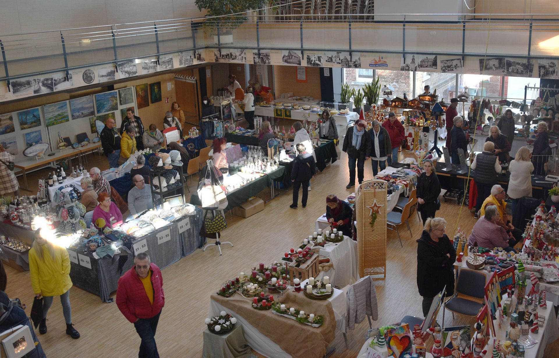 Hobbykünstlerausstellung im großen Saal des Bürgerhaus Weilmünster mit Blick von oben auf die verschiedenen Tische mit Kunst, Handwerk und Bastelarbeiten.