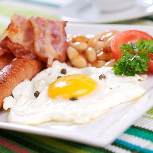 English Cooked Breakfast Eggs, bacon, sausage, beans and tomato's on a plate