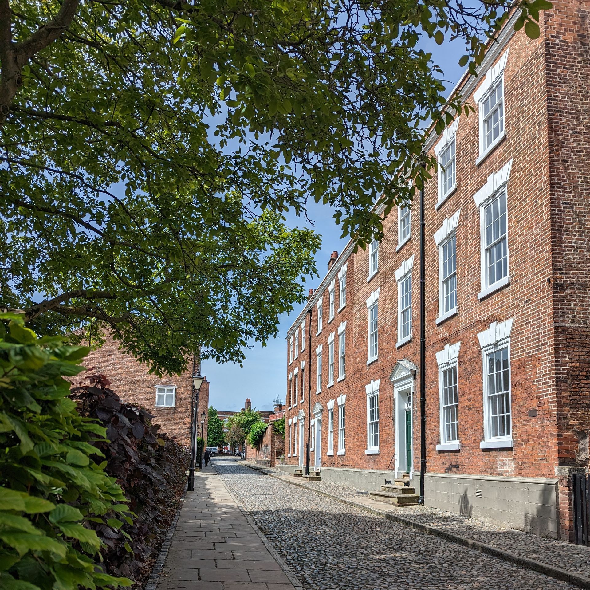 a cobbled street with victorian houses in the sunshine