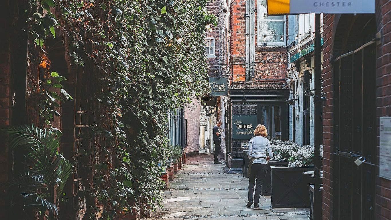 narrow cobbled street full of independent shops and trailing ivy