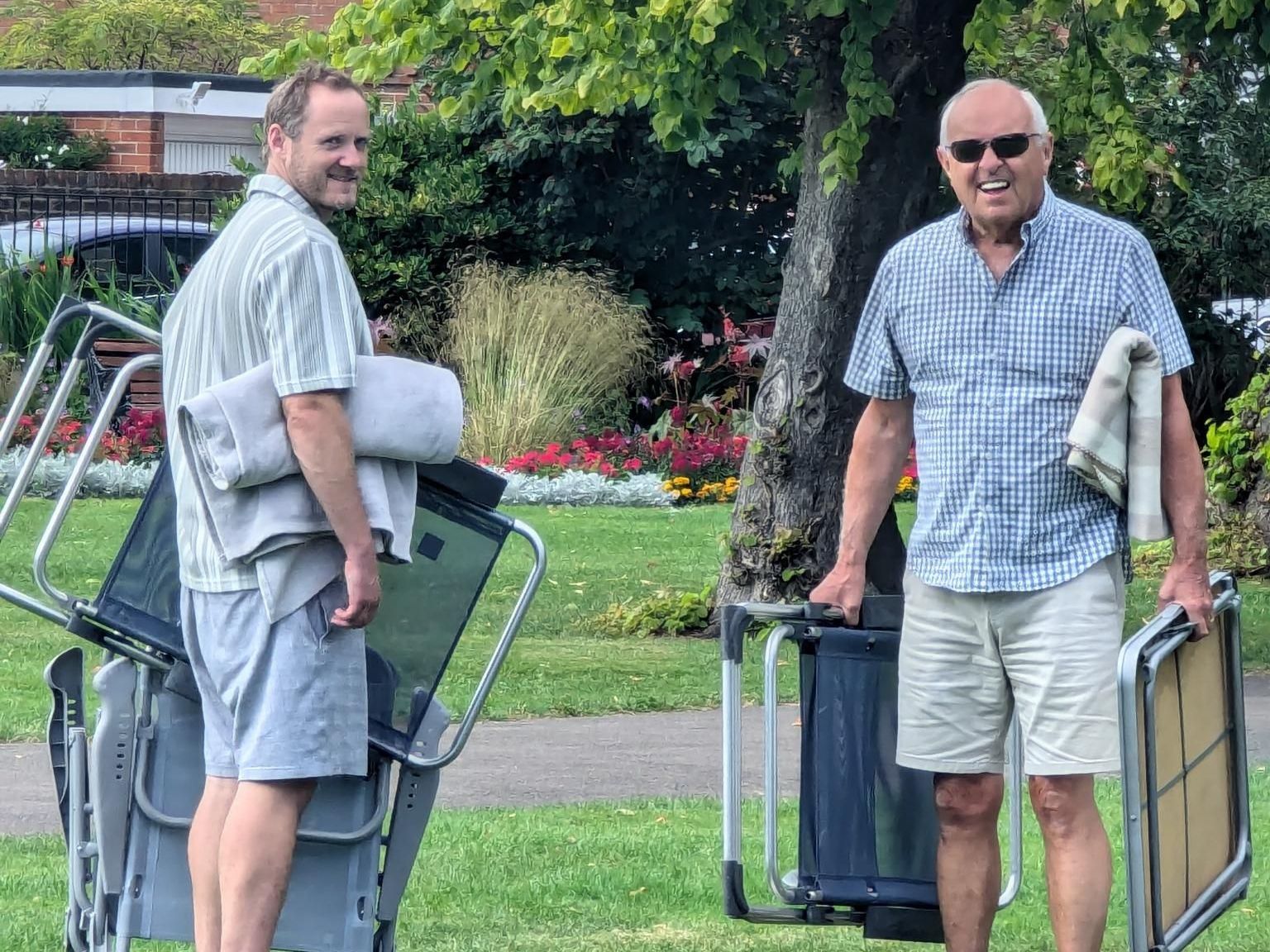 two men setting up for a picnic with deck chairs and blankets