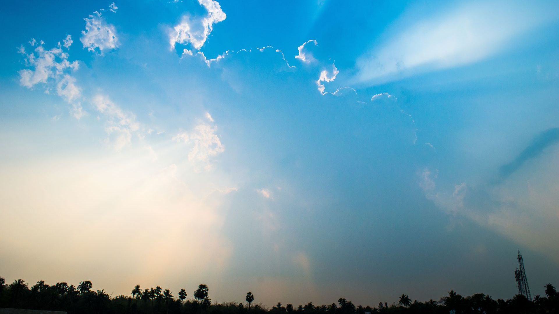 Praxis für Energietherapie Hintergrundbild. Zu sehen sind helle Wolken mit Sonnenstrahlen, die hindurchleuchten. Das Bild soll eine entspannte Atmosphäre schaffen und die Webseiten Besucher willkommen heißen.