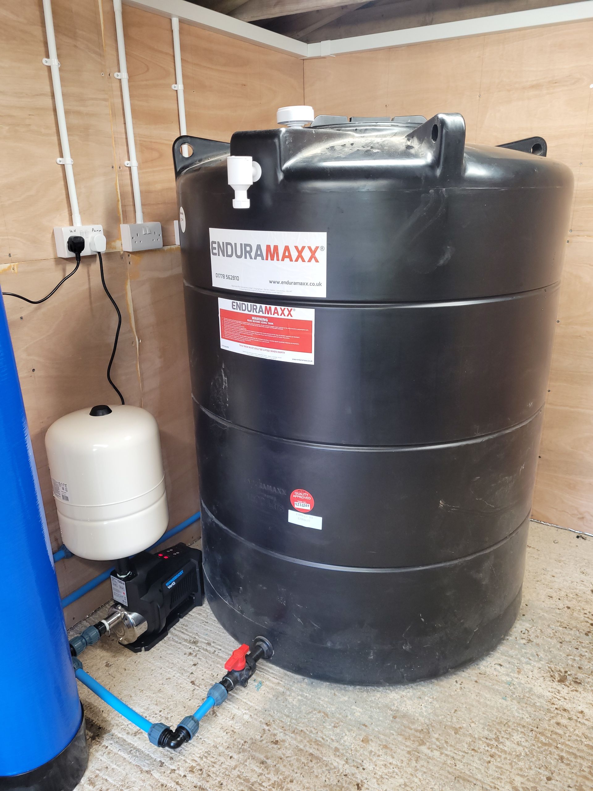 A variable speed domestic booster pump and a 3000 litre water storage tank installed at a holiday let in Pwllheli.