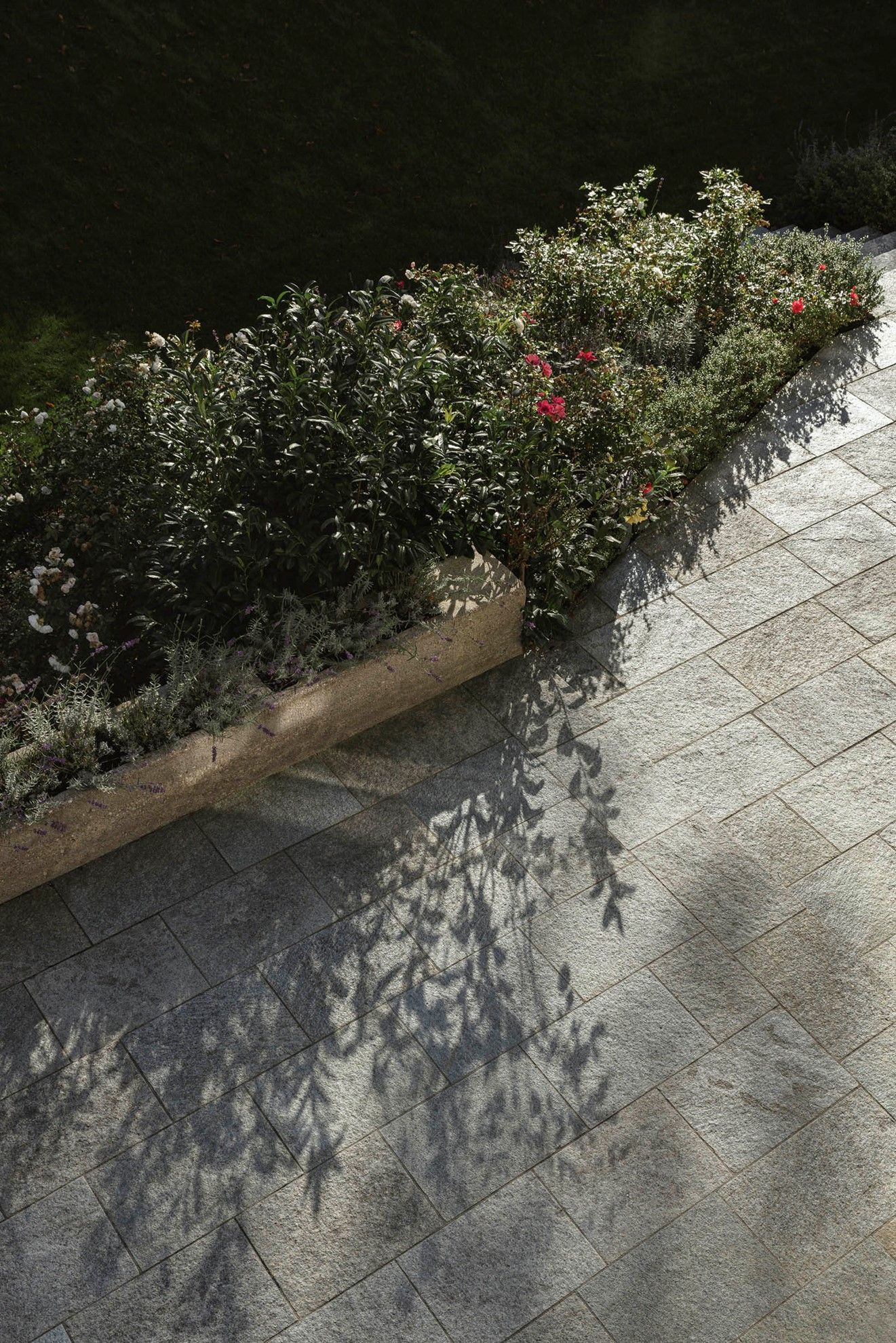Terrassenplatten aus italienischem Gneis Naturstein in Hellgrau am Blumenbeet