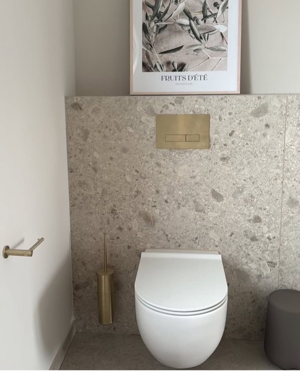 Ceppo di Gre Natursteinoptik an WC Rückwand Großformat, goldene Armaturen und weißes WC.