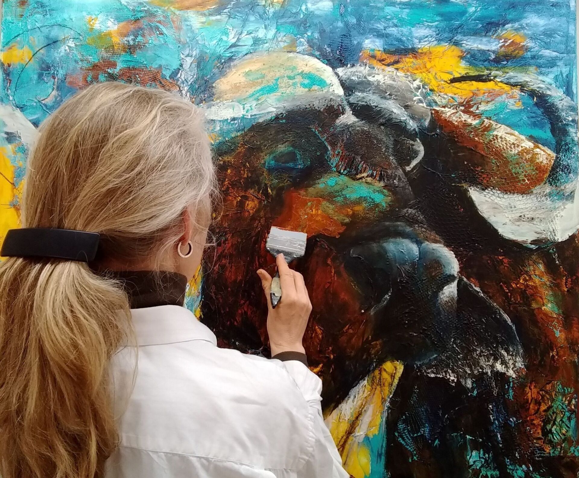 Bianca Leidner malt mit Spachtel rötliche Farbe auf das Portrait eines Büffels