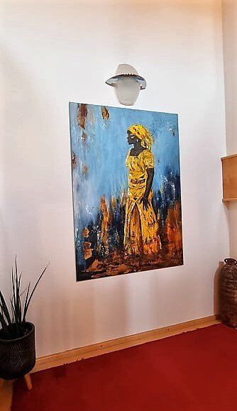 großformatiges Bild einer stolzen afrikanischen Frau im gelben Kleid an der Wand einer Kundin