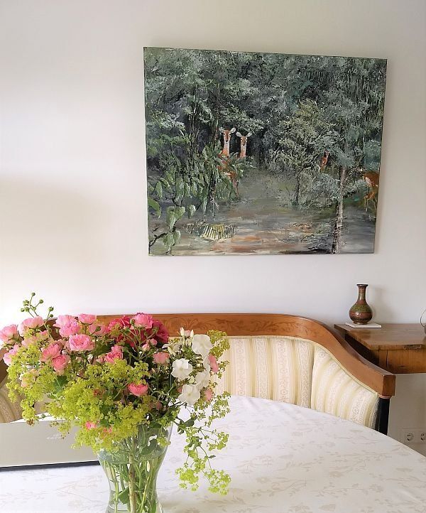 Bild mit Buschböcken an einer Wand, davor ein Sofa und ein Tisch auf den ein schöner Blumenstrauß steht. Überwiegende farben: grün, braun, beige, rosa
