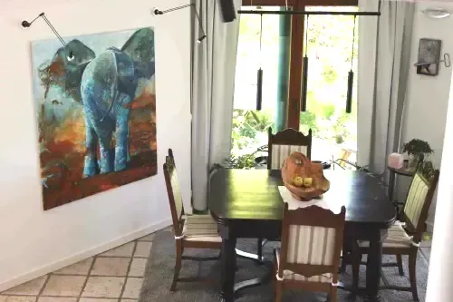 Gemälde eines blauen Elefanten von hinten in rostroter Umgebung an der Wand eines Esszimmers