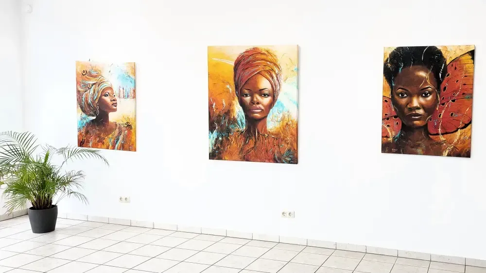 3 Gemälde mit Portraits von afrikanischer Frauen an einer Wand