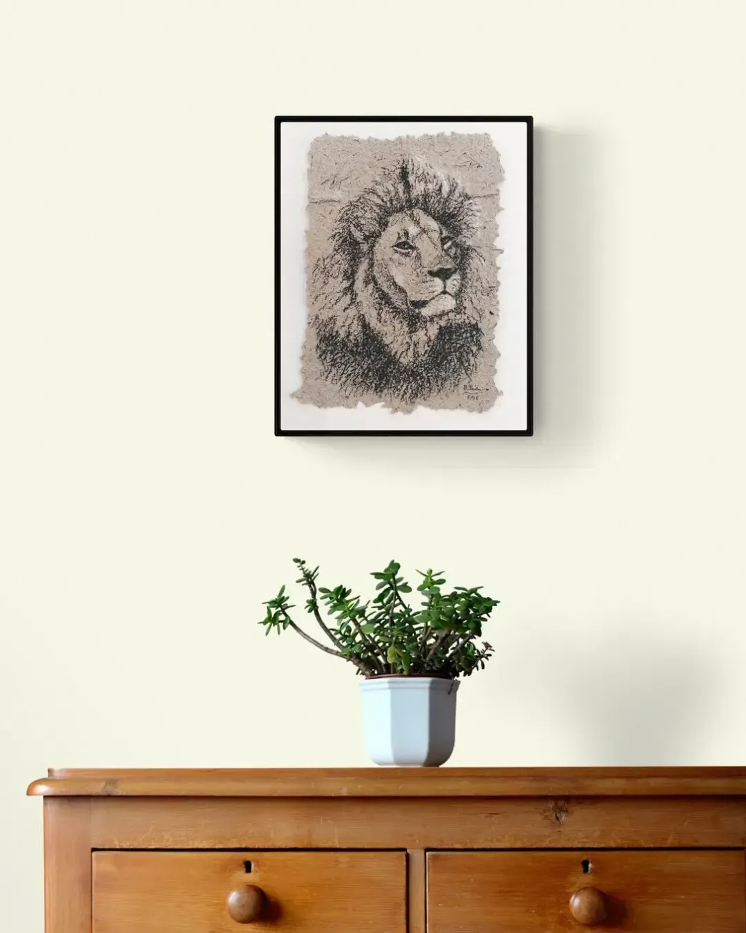 Löwenportrait mit Kohle auf Elefantenpapier gerahmt an der Wand über einer Komode