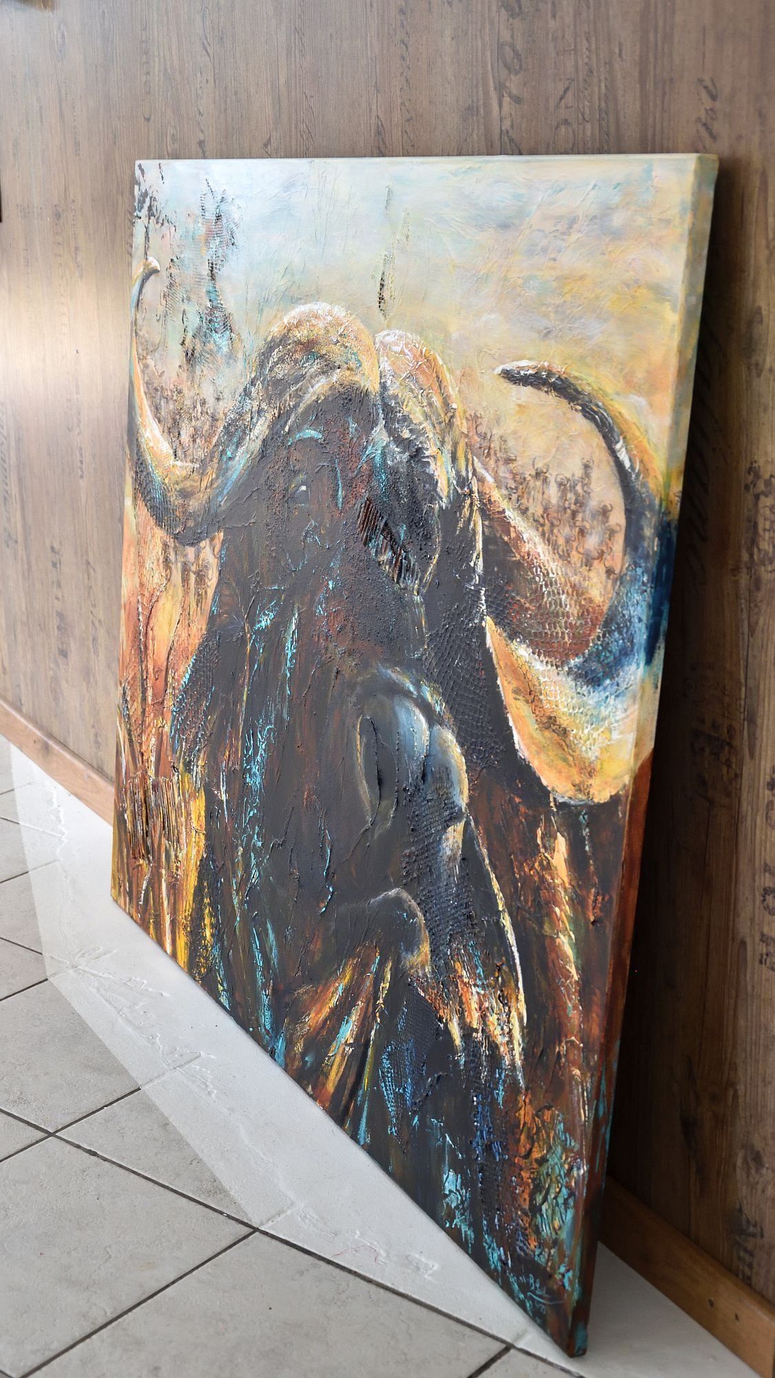 Portrait eines afrikanischen Büffels steht an eine Wand gelehnt, so dass man die bemalten Seiten des Gemäldes sehen kann