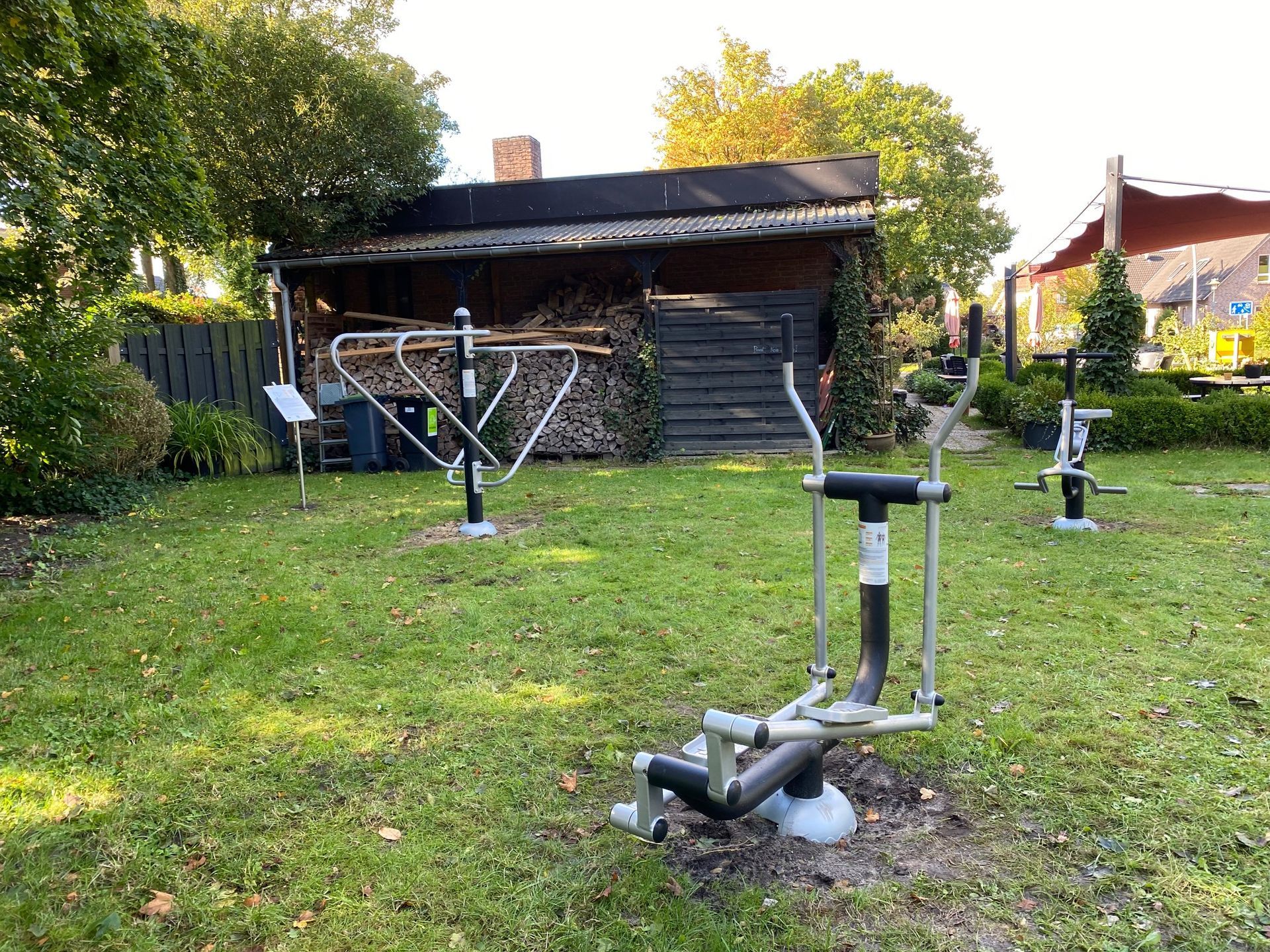 Outdoor-Fitnessgeräte auf einer kleinen Wiese mit einem Schuppen im Hintergrund