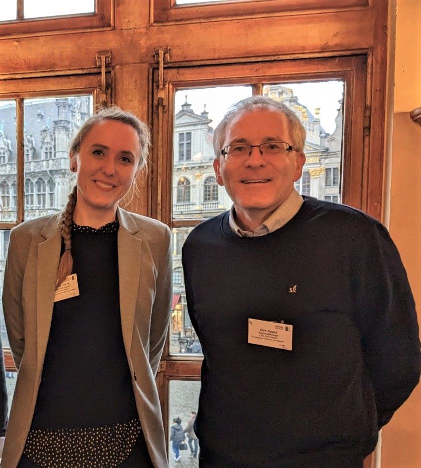 zwei Personen, die vor einem Fenster stehen und in die Kamera lächeln zwei Personen, die vor einem Fenster stehen und in die Kamera lächeln