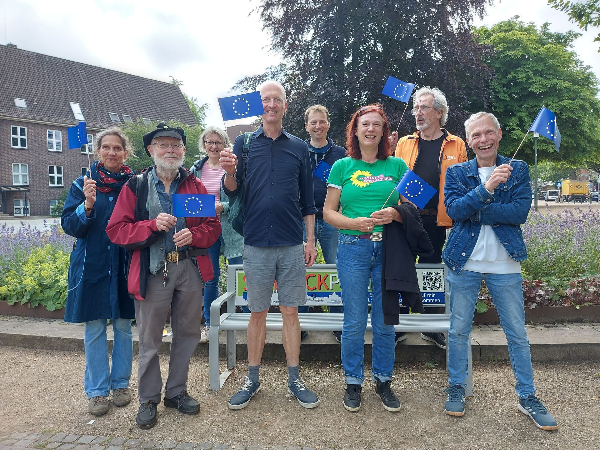 Mehrere Männer und Frauen, die mit einer kleinen Europa-Flagge in der Hand, in die Kamera lächeln Mehrere Männer und Frauen, die mit einer kleinen Europa-Flagge in der Hand, in die Kamera lächeln