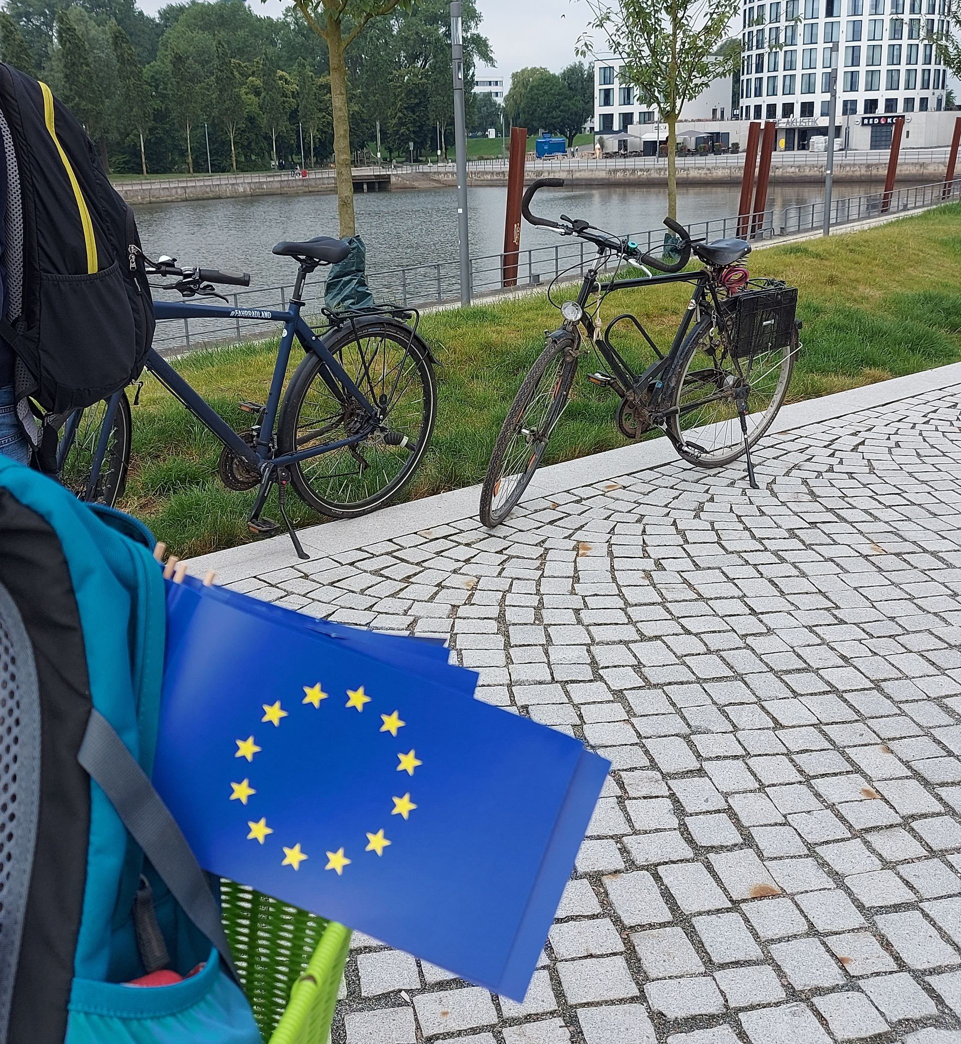Fahhräder am Straßenrand, Rucksack mit Europa-Flaggen Fahhräder am Straßenrand, Rucksack mit Europa-Flaggen