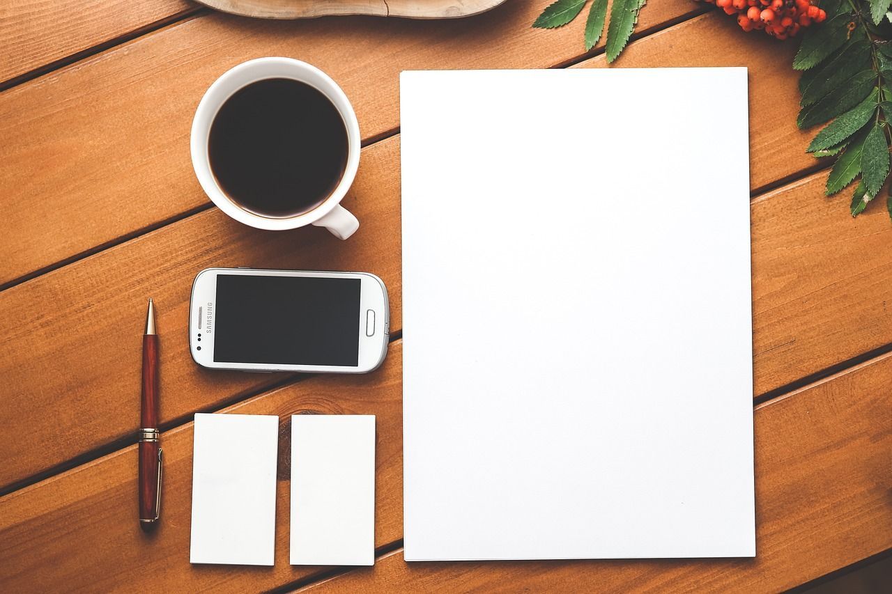 Kaffeetasse, Handy, Stift und Notizblöcke von oben fotografiert Kaffeetasse, Handy, Stift und Notizblöcke von oben fotografiert