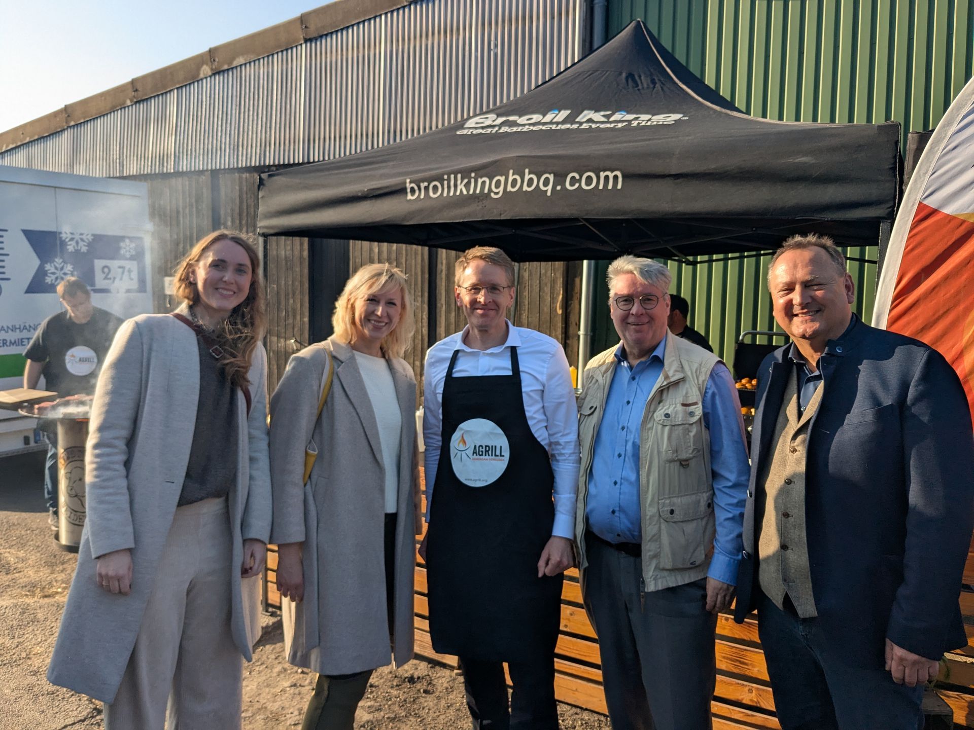 Ministerpräsident Daniel Günther umringt von drei weiteren Personen vor einem Grill Ministerpräsident Daniel Günther umringt von drei weiteren Personen vor einem Grill