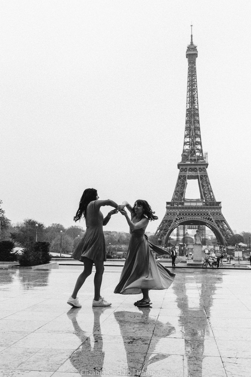 two girls dancing in the rain in front of the eiffel tower in paris