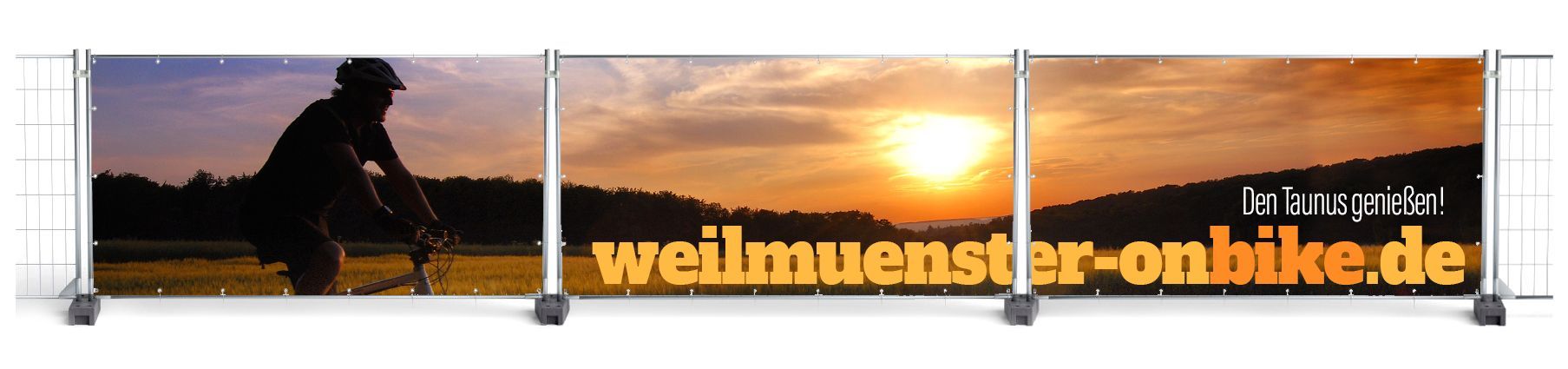 Bauzaun-Motive als Sichtschutz mit einem Radfahrer im Taunus bei Sonnenuntergang