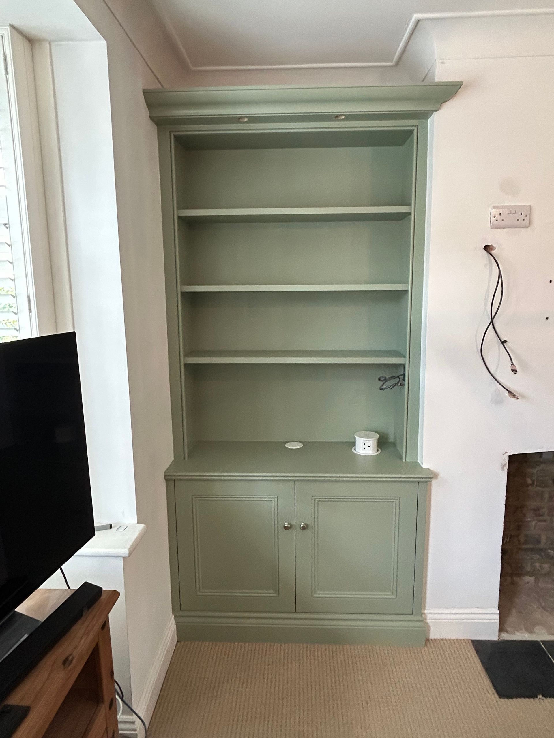 Traditional alcove cupboards with bespoke bookcase above, integrated downlights and pop-up electrical socket fitted in Teddington