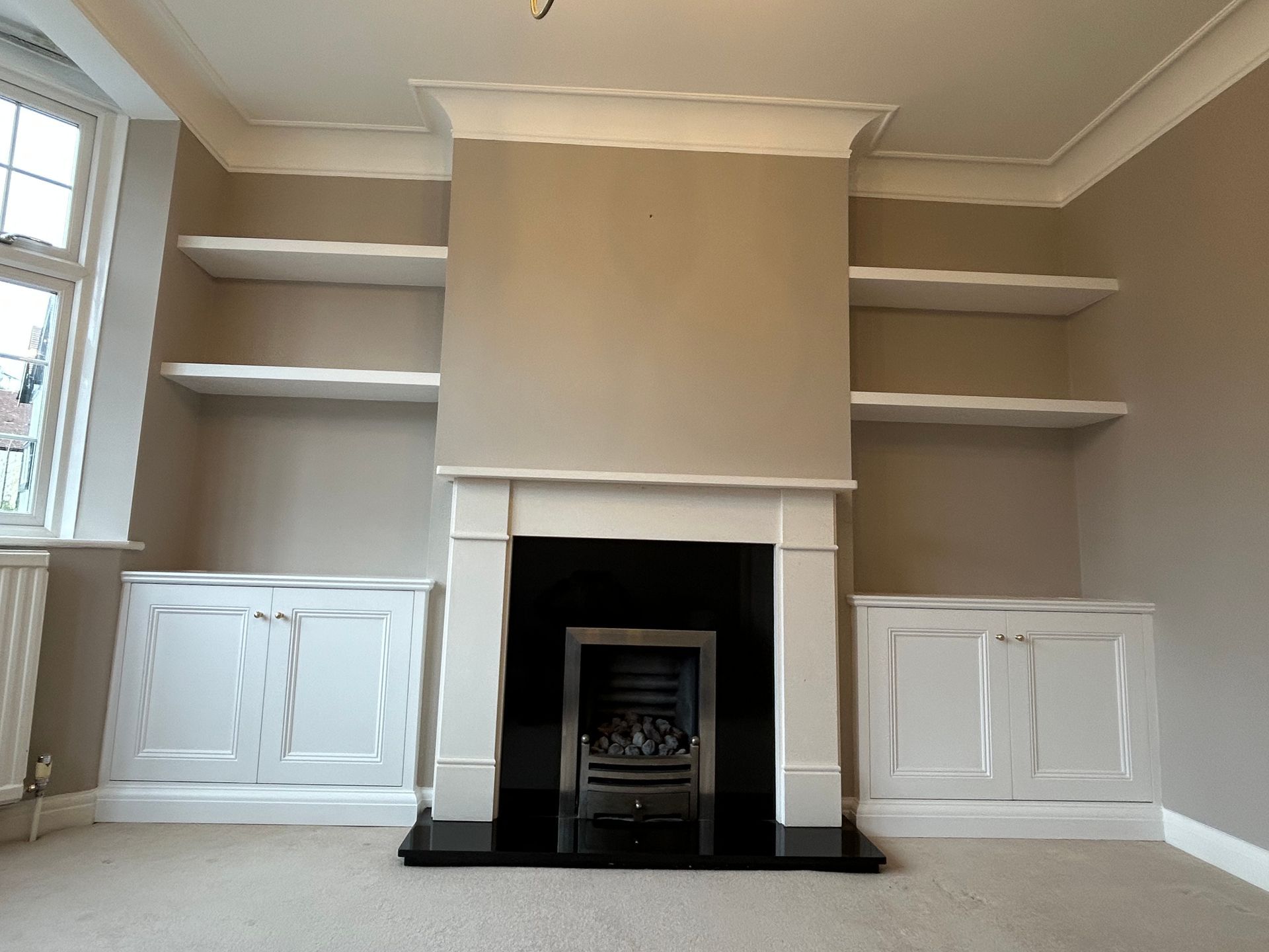 Traditional alcove cupboards and floating shelves beside chimney breast in Kew