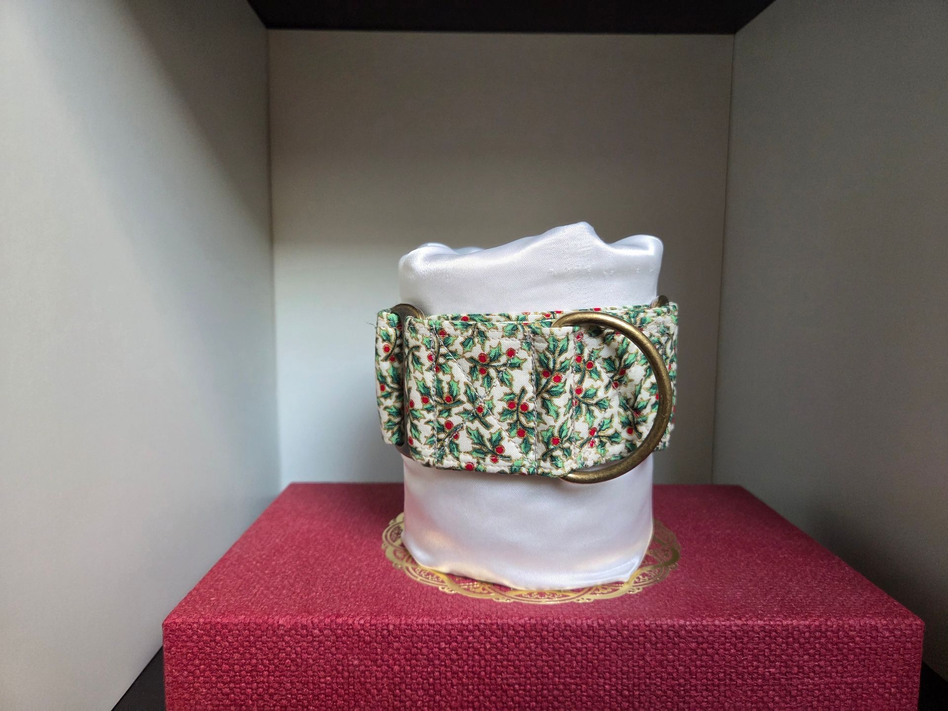 Martingale pour lévriers en tissu clair imprimé de feuillages verts et de petites baies rouges. Anneaux métal finition laiton. Confortable, réglable et fait main, idéal pour galgos, whippets, podencos.