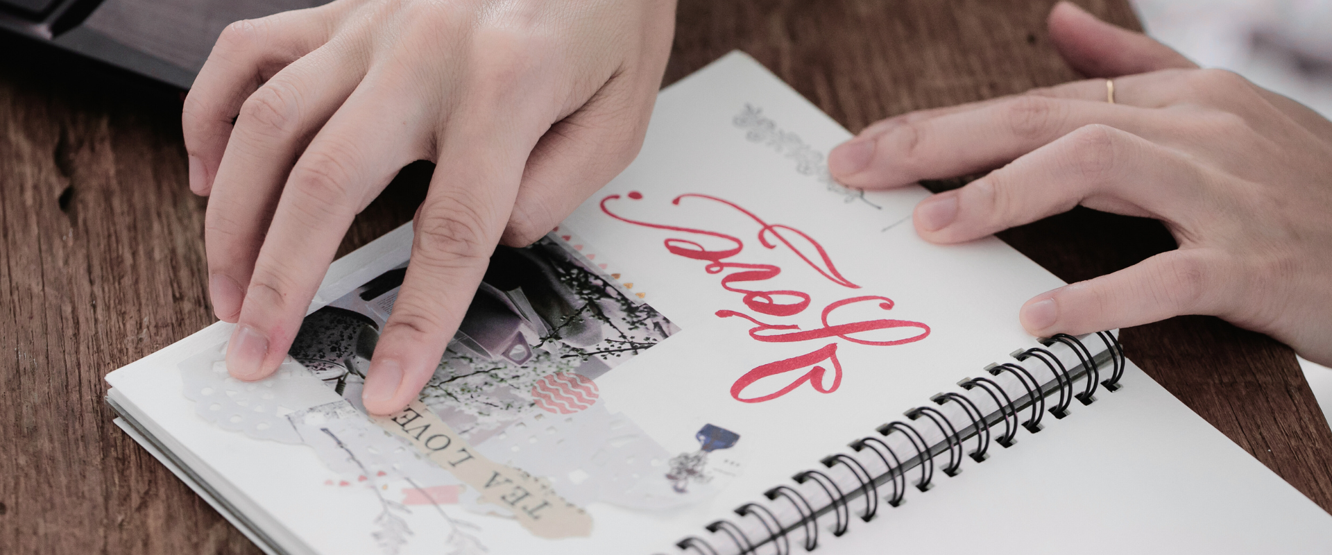 Offenes Vision Book mit Collage aus Bildern, Worten und Naturfundstücken, auf Holztisch draussen