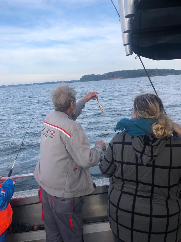 Angelguiding Jan hilft gerade einem Angler beim Angeln.