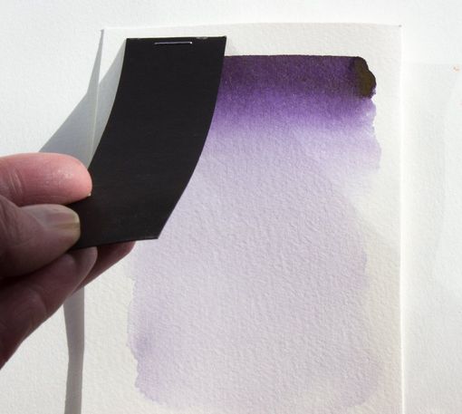 Lifting the black paper cover of a graded watercolour wash to assess colour change after exposing to direct sunlight. Checking a watercolour wash for colour changes .