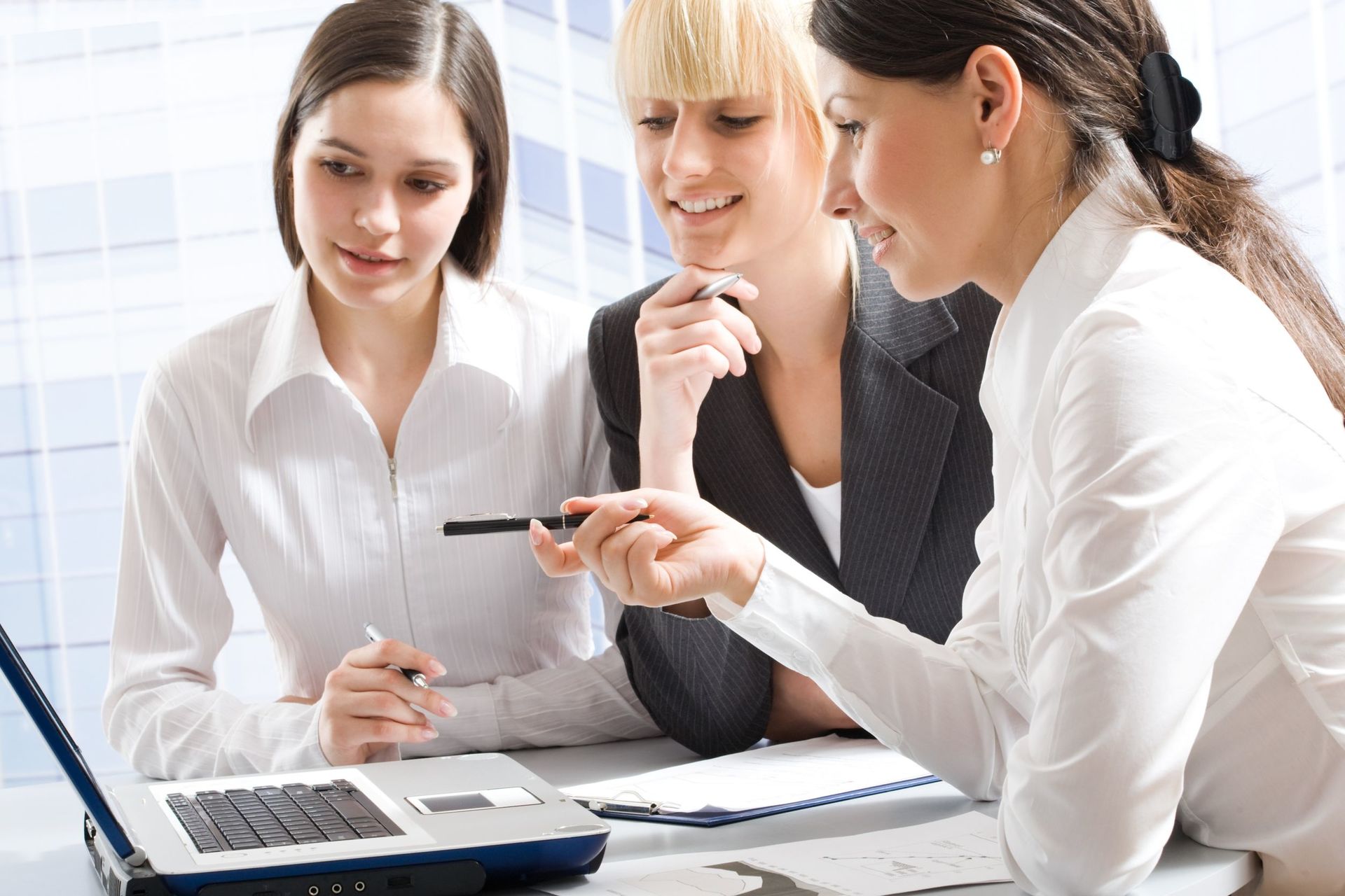 Tre ragazze che svolgono formazione in abito business con computer
