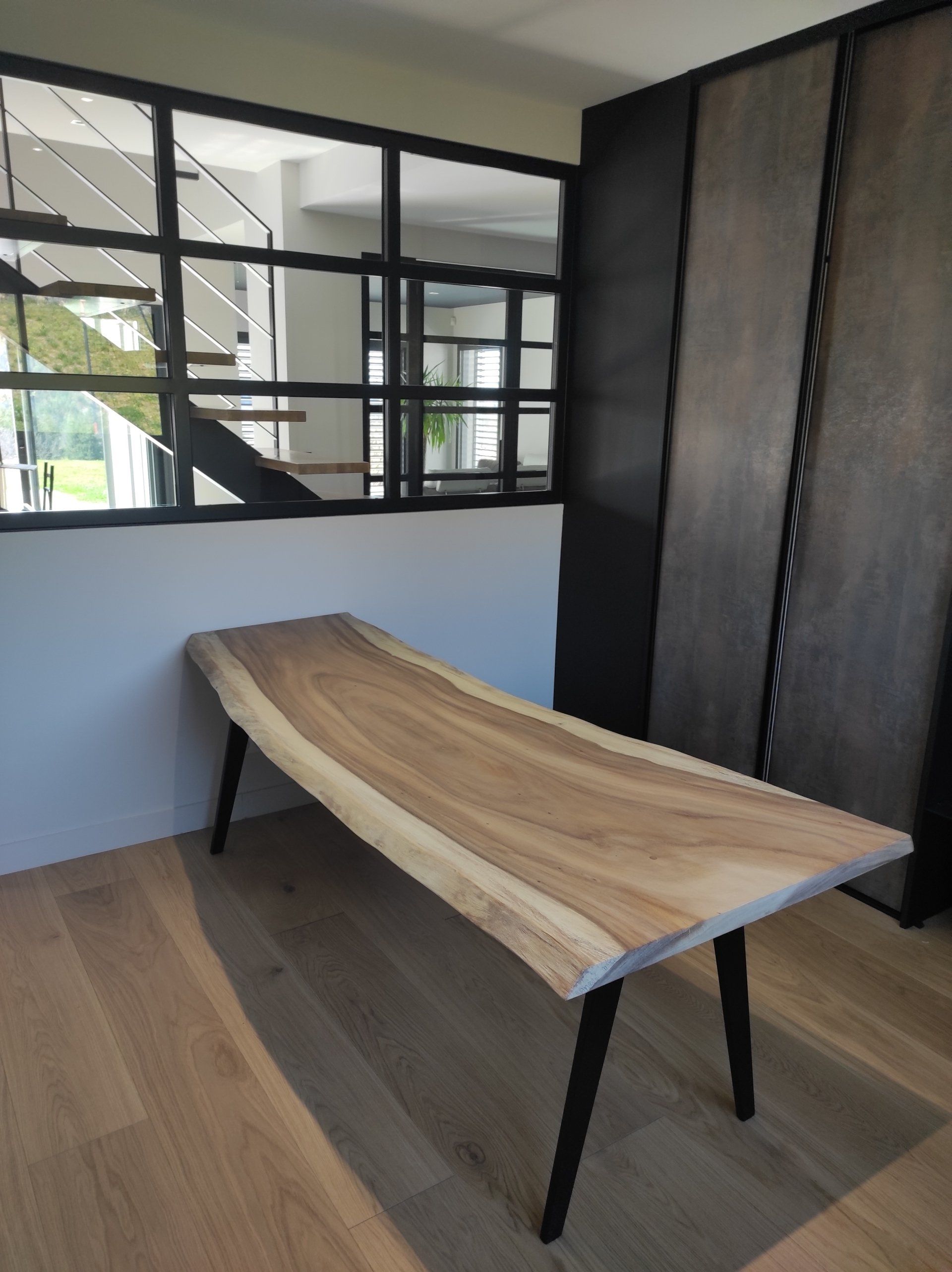 Bureau bois massif brut sur mesure, plateau unique à bord naturel (live edge) dans une maison moderne.