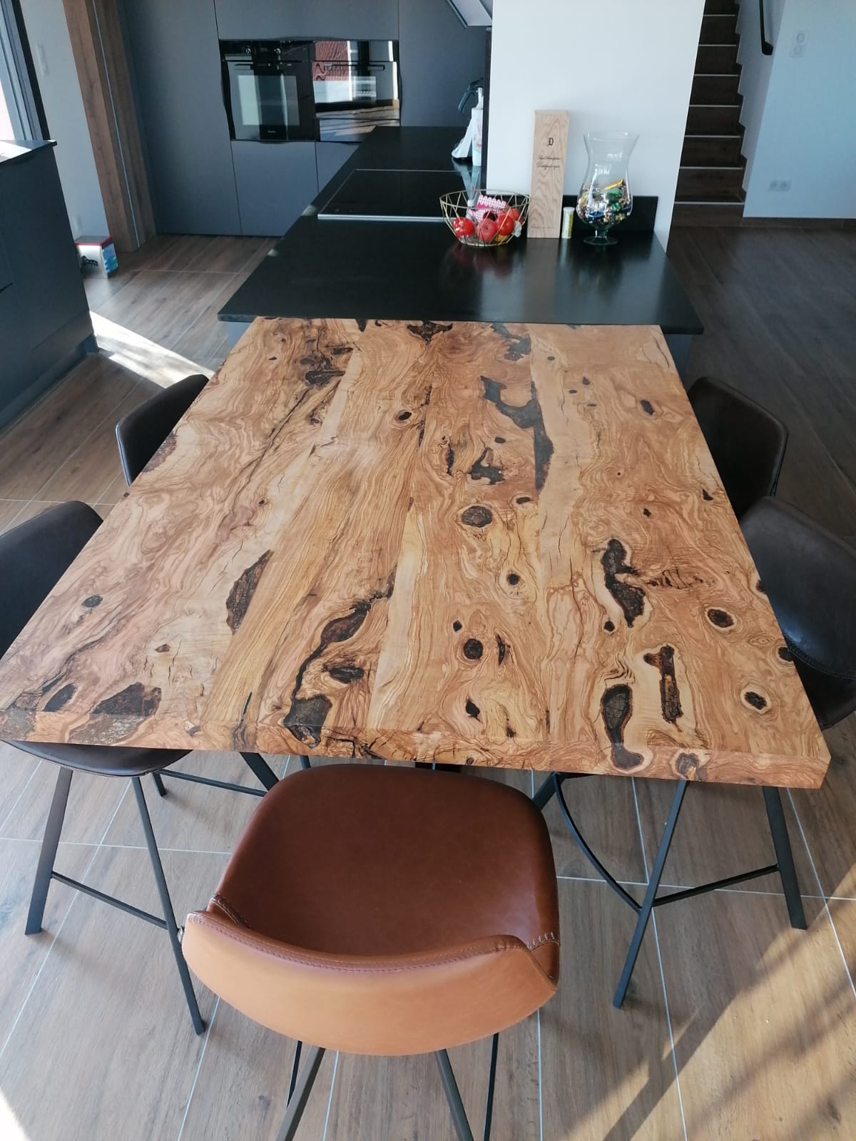 Table familiale en bois d'olivier huilé, ici sous forme d'un prolongement d'îlot de cuisine.