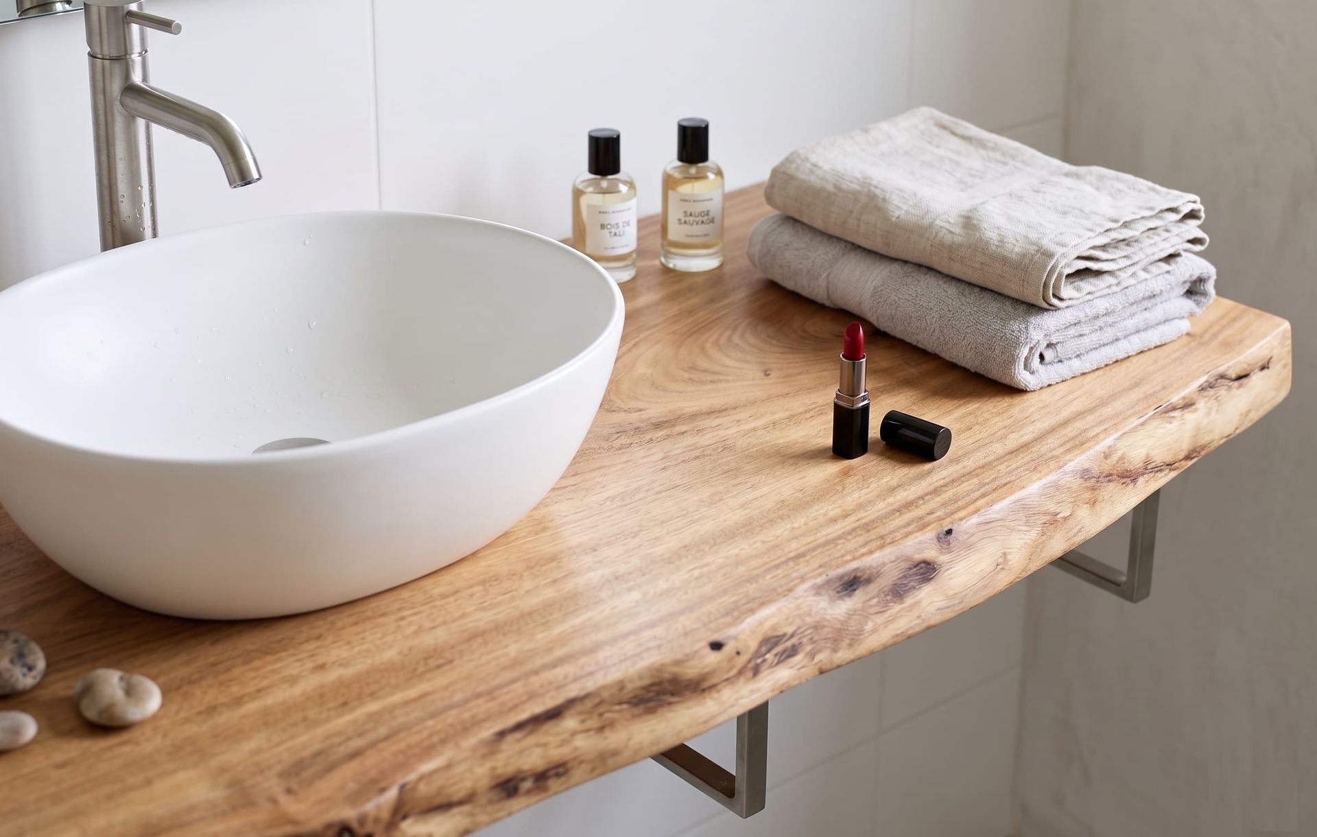 Meuble de salle de bain suspendu en bois de Tali massif au bord naturel brut, conçu pour une haute résistance à l'humidité et une protection contre les taches de maquillage, avec vasque bol blanche et accessoires.