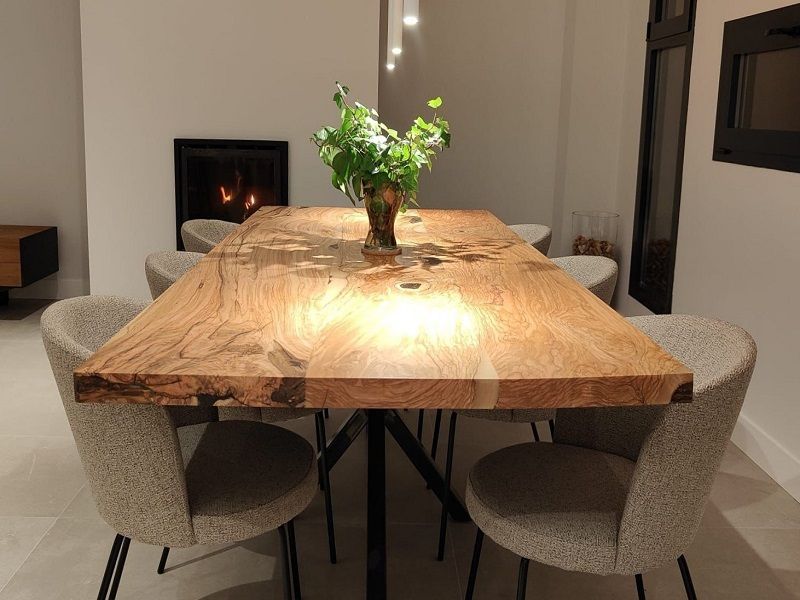Table rectangulaire réalisée sur mesure en bois d'olivier massif entourée de jolies chaises grises.