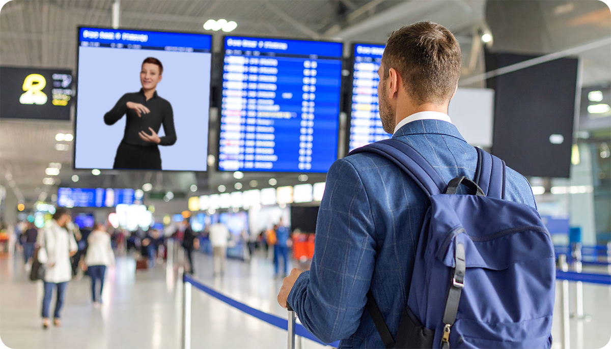 Mann steht vor einem Gebärdensprach-Avatar Informationsbildschirm am Flughafen