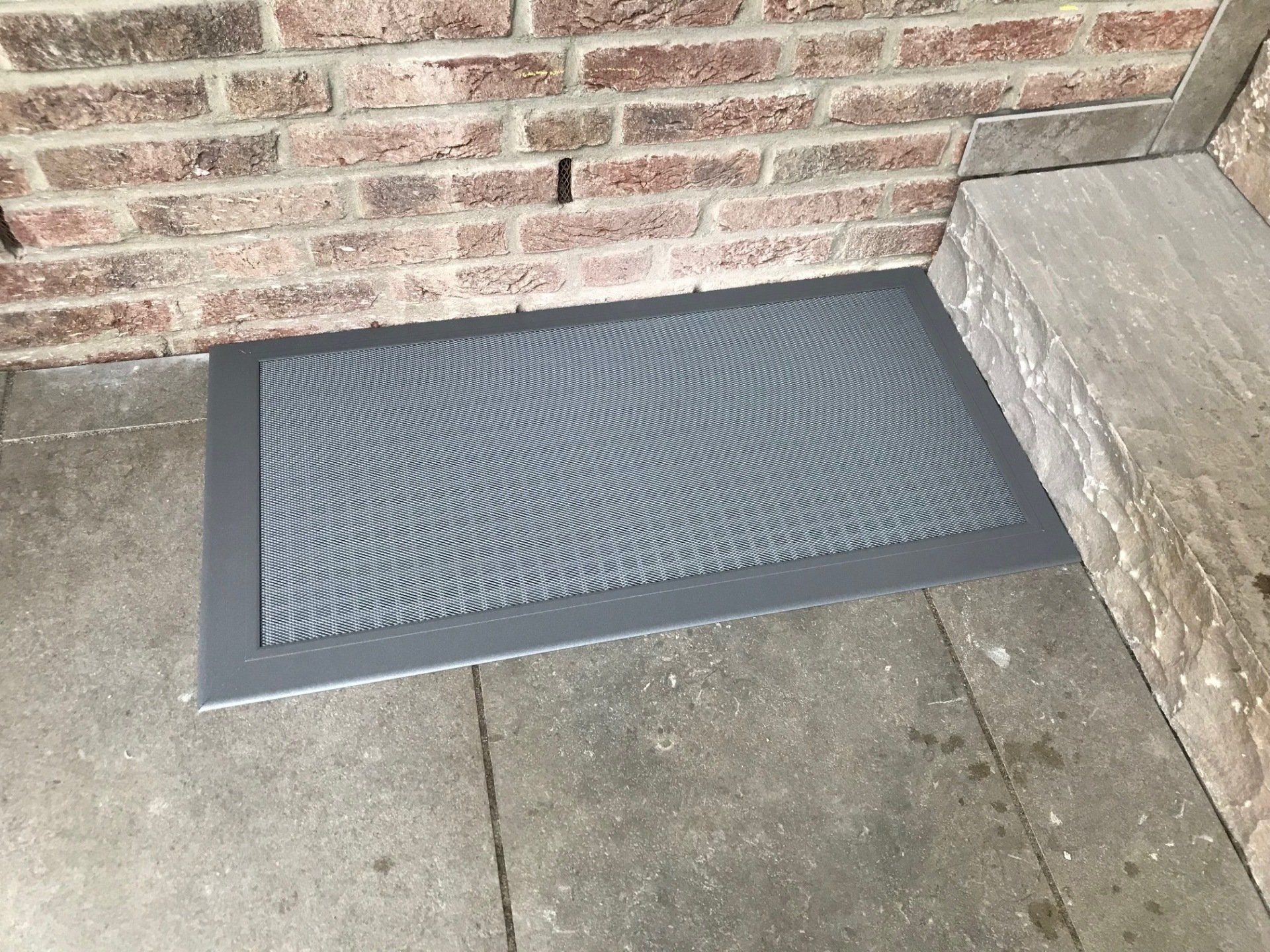 Begehbare Lichtschachtabdeckung aus Aluminium mit feinmaschigem Gitter, passgenau in der Terrasse montiert