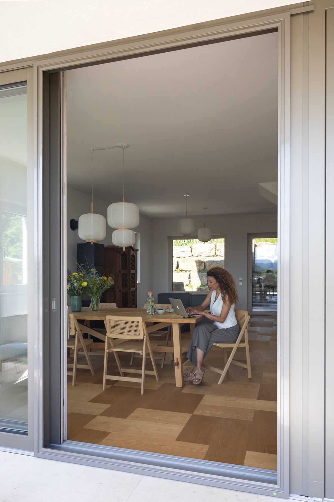 ISK Systeme Insektenschutz-Schiebeanlage an einer großen Terrassentür ermöglicht angenehmes Arbeiten bei geöffneter Tür und schützt zuverlässig vor Insekten.